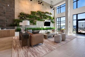 Modern lobby with green wall, large windows, stylish furniture, and hanging lights.