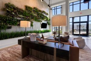 Modern lobby with vertical garden, large windows, cozy seating, and stylish lamps, creating a welcoming atmosphere.