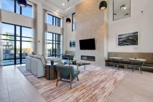 Modern living room with high ceilings, fireplace, cozy seating, large windows, and stylish decor elements.