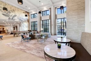 Modern hotel lobby with elegant seating, large windows, artistic wall mural, and pool table for relaxation and comfort.