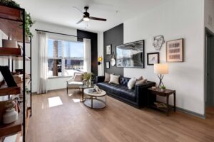 Modern living room with black sofa, wood floor, large window, and stylish decor. Cozy and bright interior design.