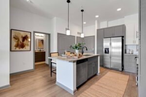 Modern kitchen with an island, pendant lighting, gray cabinets, and stainless steel appliances.
