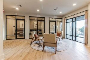 Modern office lounge with stylish chairs, glass partitions, and large windows, offering a bright and inviting space.