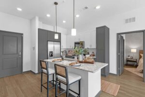 Modern kitchen with an island, bar stools, granite countertops, and pendant lighting in a cozy apartment setting.