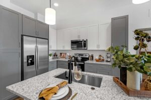Modern kitchen with granite countertops, stainless steel appliances, and gray-white cabinetry.