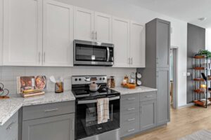 Modern kitchen with gray and white cabinets, stainless steel appliances, and sleek countertop decor.