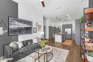 Modern living room with a leather sofa, wall art, and a stylish kitchen island in view.