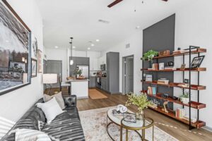 Modern living room with stylish decor, leather sofa, glass coffee table, and open kitchen in the background.