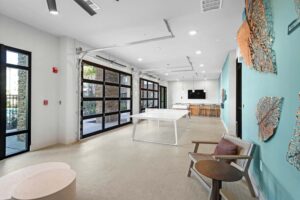 Modern recreational room with table tennis, bar, and unique wall art, featuring large windows for natural light.